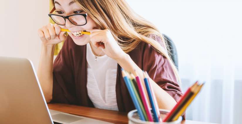 Girl at laptop biting pencil